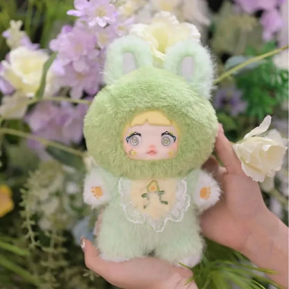 Green plush toy with floral design held in front of flowers and greenery,Nommi V3 Interesting Fruit Dolls Series Dolls plush blind box — Avocado (mint green) — Kuwait — نومي