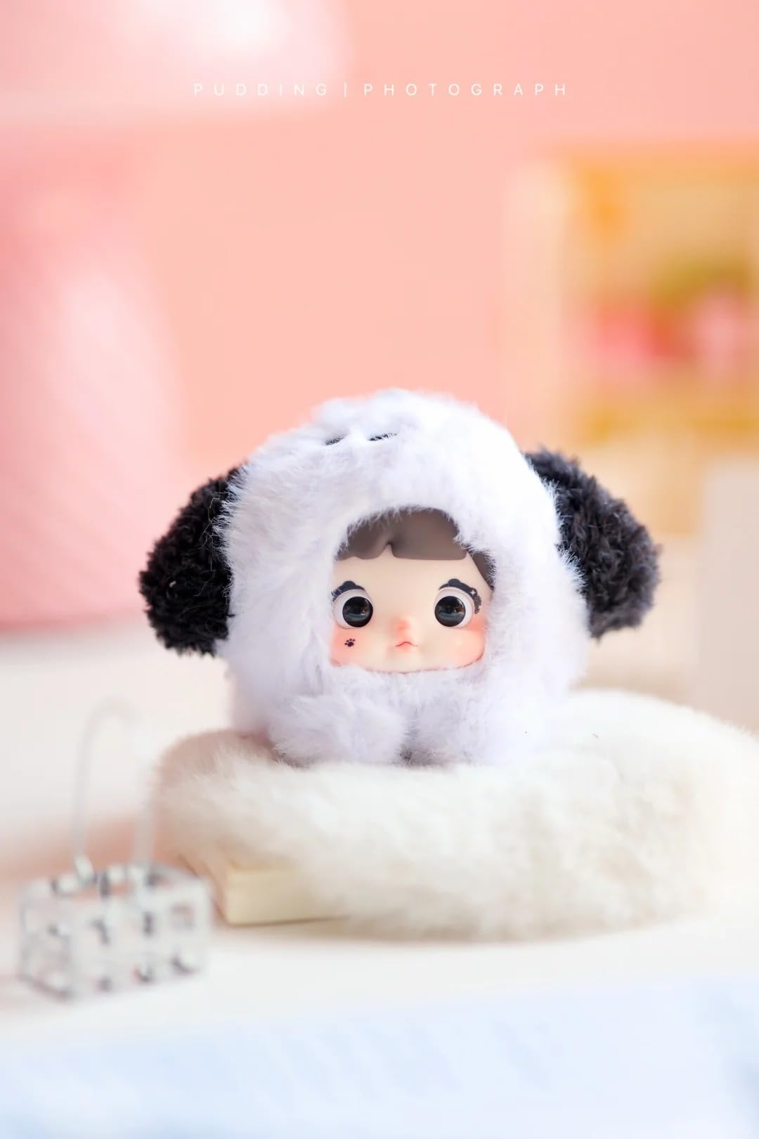 Plush toy resembling a character with black and white fur on a soft surface.Nommi V4 Baby Series plush key chain blind box — Spotty Baby (white/black) — Kuwait — نومي — Maibo