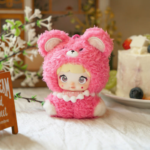 Pink teddy bear plush toy with a doll's face on a table with decorative items in the background,Nommi V4 Baby Series plush key chain blind box — Straw Baby (rose pink) — Kuwait — نومي — Maibo