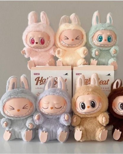 Plush toys resembling cartoon characters with colorful eyes and various expressions, standing in front of boxes labeled 'Hatsune Miku'.Pop Mart Labubu Have a Seat V2 blind box — all colors (SISI/DADA/QUQU/ZIZI/HEHE/BABA) — Kuwait — لابوبو الاصدار الثاني